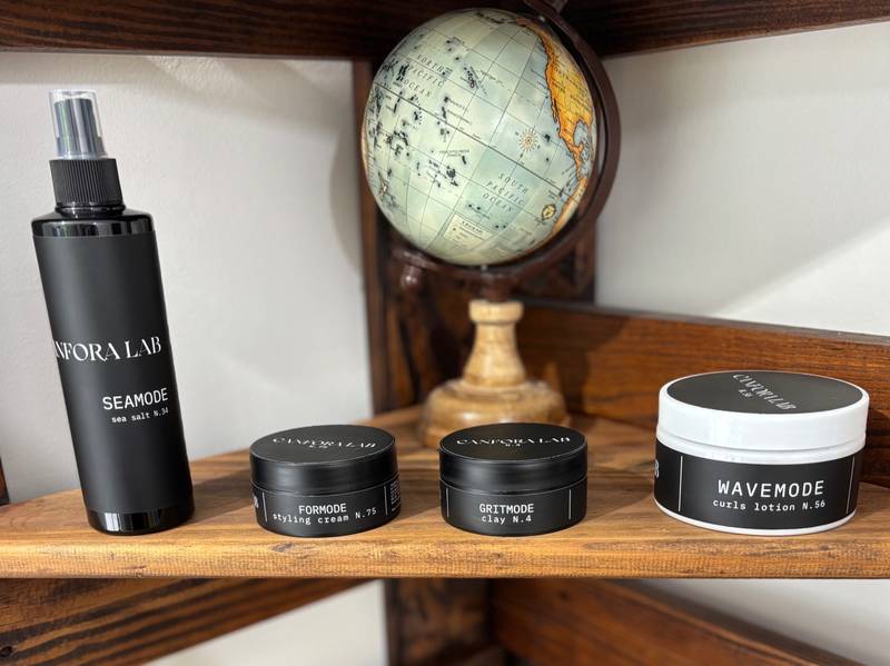 Canfora Lab grooming products collection – Seamode Sea Salt Spray, Formode Styling Cream, Gritmode Clay, and Wavemode Curls Lotion displayed on wooden shelf