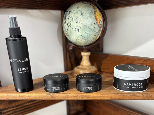 Canfora Lab grooming products collection – Seamode Sea Salt Spray, Formode Styling Cream, Gritmode Clay, and Wavemode Curls Lotion displayed on wooden shelf